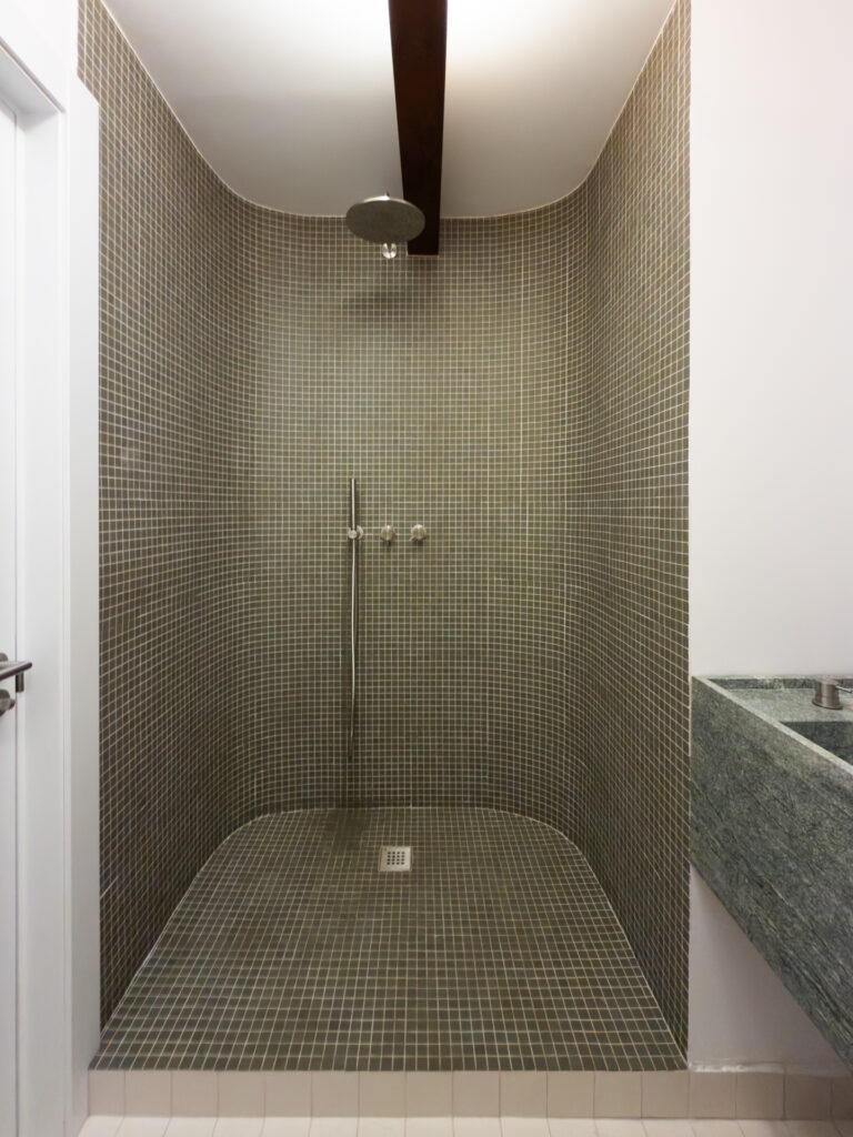Baño de Casa Vega con gresite granate y radiador toallero, con grifería empotrada de acero cepillado