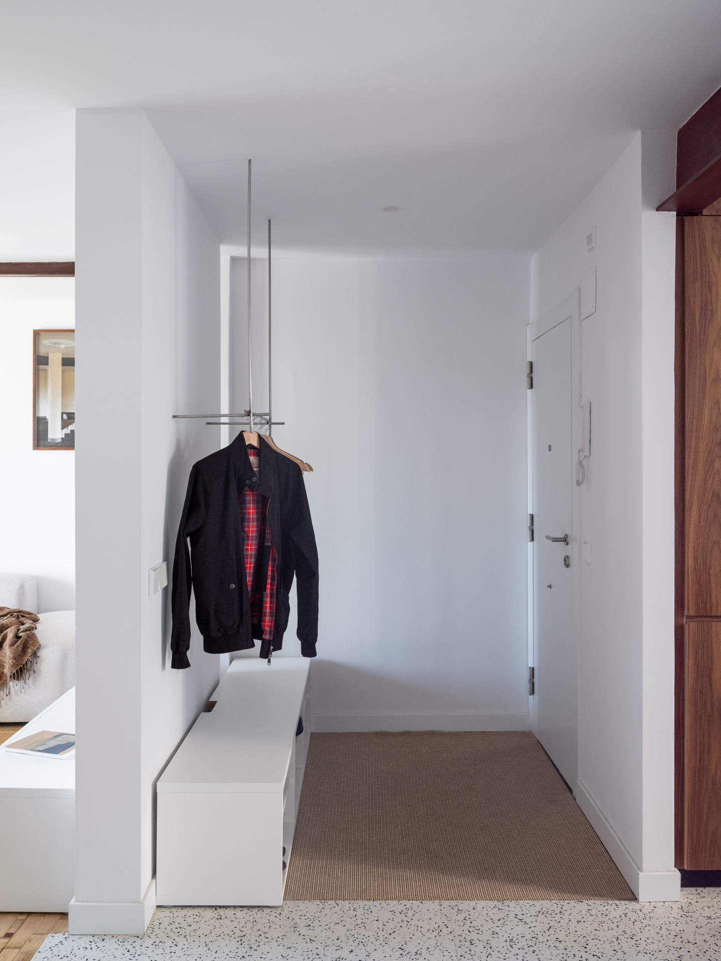 Entrada de casa Vega con espacio para colgar abrigos y zapatero con banco para calzarse